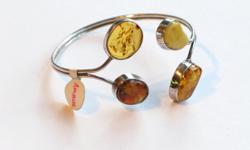 4 large, freeform pieces of amber surrounded by 925 sterling silver, set to be squeezed into position on wrist for fit and choice of design. All 4 amber pieces are different; 2 are approx. the size of a nickel, 2 about the size of a dime. Very nice color