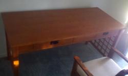 Large Dark Oak desk with matching cushioned chair on rollers. Desk is 26x58 In perfect condition. Waffle pattern of same wood on sides of desk.