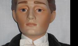 Gibson Groom Heirloom Doll is a porcelain doll from the Franklin Mint. He is approximately 23 inches tall with brown sculpted hair and blue eyes. He is wearing a black tuxedo. He comes with a Certificate of Authenticity, hang tag, stand, and box.
Gibson