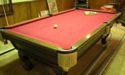 8-foot pool table, with leather pockets with gold bullion fringe, one inch thick Brazilian slate base in three parts, red felt top, and Queen Anne legs. Imperial is the manufacturer. Color is medium brown red oak. This table is in great condition. The
