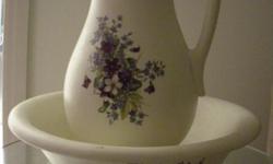 Wash bowl and pitcher in the Victorian style. It is a reproduction, one-of-a-kind and handmade by artisans in a creamy white color and has lovely purple flowers on the face of the pitcher. The pitcher stands approx. 13? high x 8? wide. The bowl is approx.